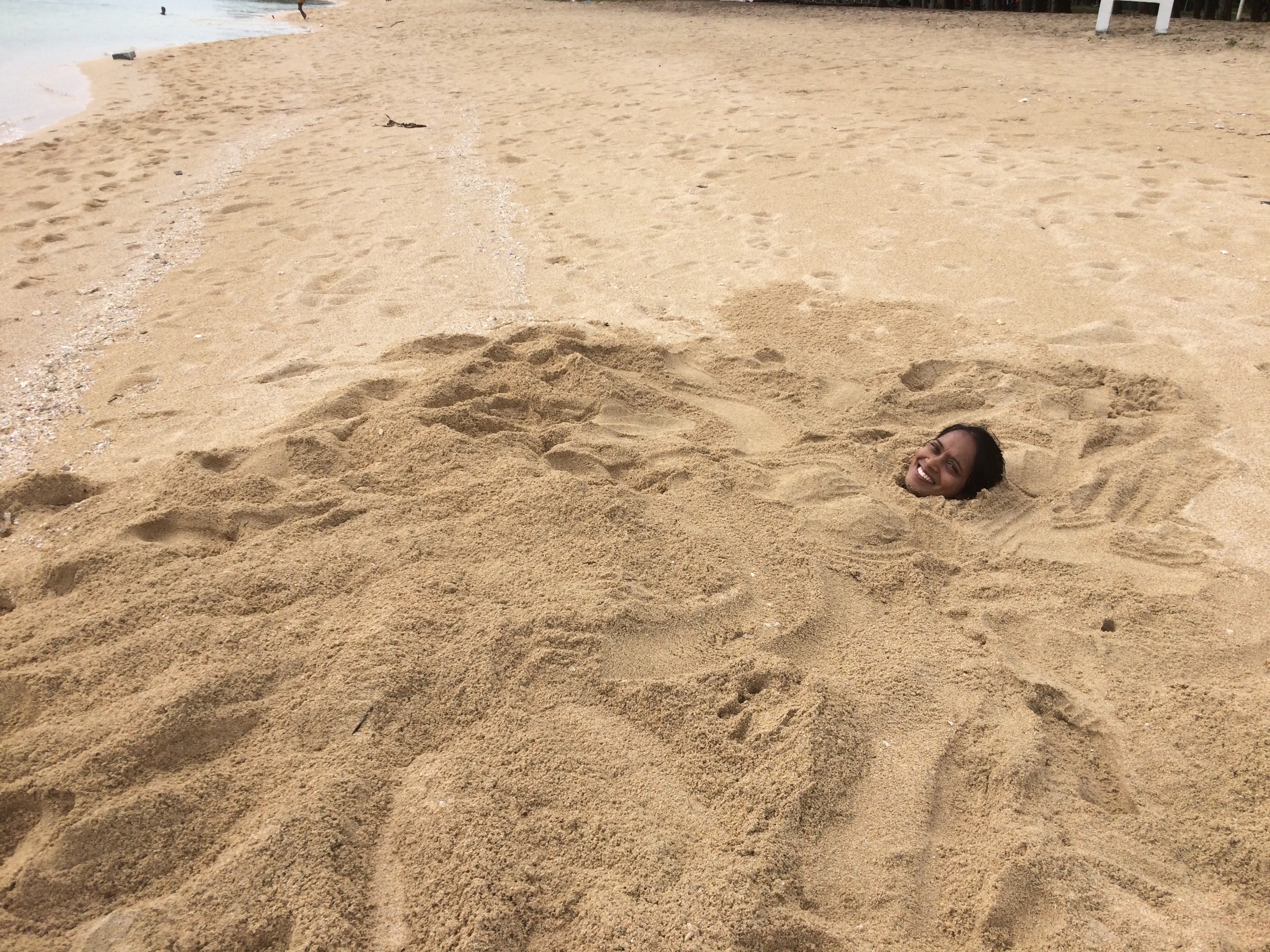 Vanishta Changea buried in the sand on a beach in Mauritius